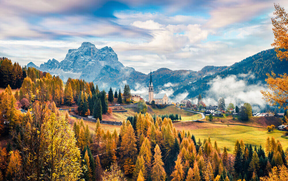 Foggy autumn view of Parrocchia Di Selva Cadore church. Great morning scene of Dolomite Alps, Cortina d'Ampezzo, southern Alps in the Veneto region of Northern Italy, Europe. Italy in September