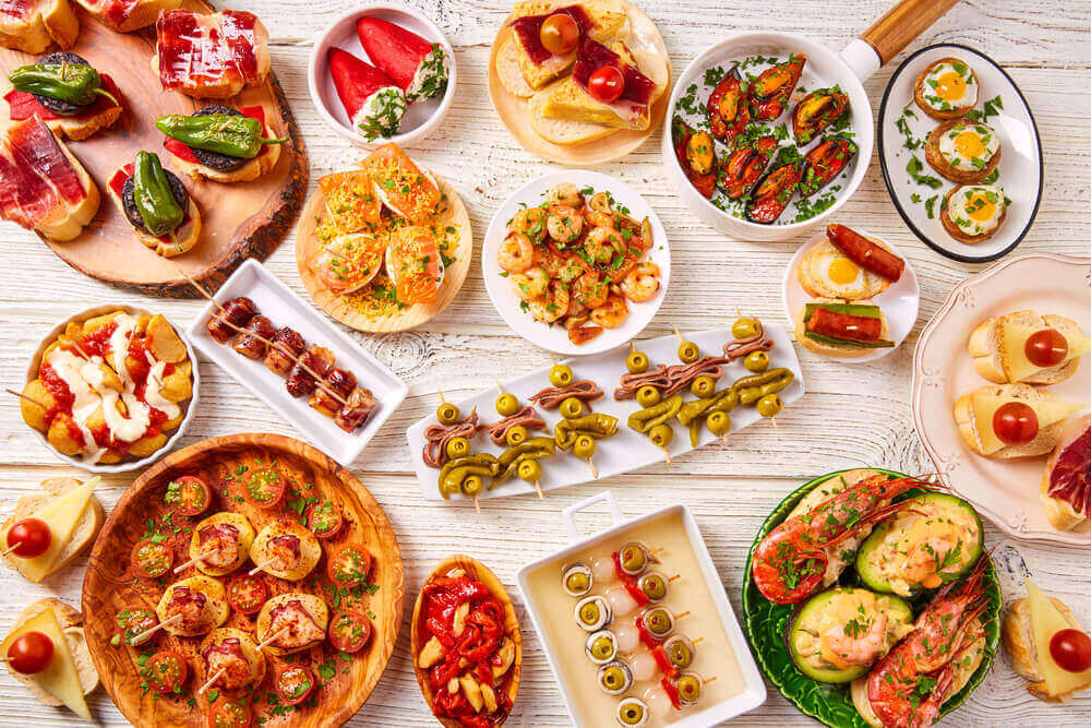 Tapas mix and pinchos food from Spain recipes also pintxos on a white wood board. Tapas In Spain