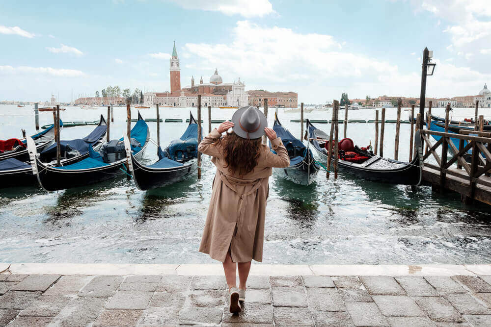 Young woman in a hat on a background of water in Venice. Italy in September